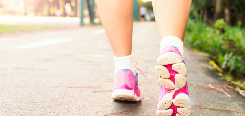 photo of woman wearing pink sports shoes walking
